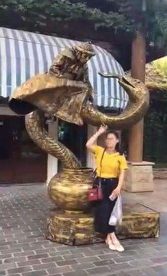 美女跟铜像合影，铜像却突然流出了水，美女转头一看被吓了一跳