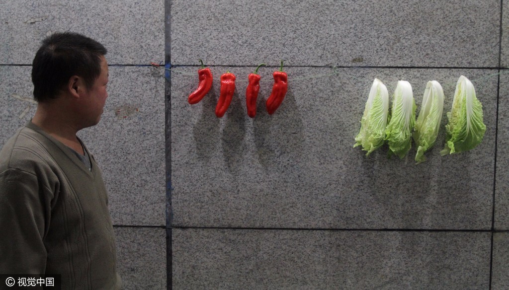 杨树成将4棵大白菜,4个红辣椒挂在自己厨房的墙上,很美观.